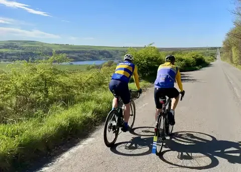 Two Imps riders cruising along a reservoir road
